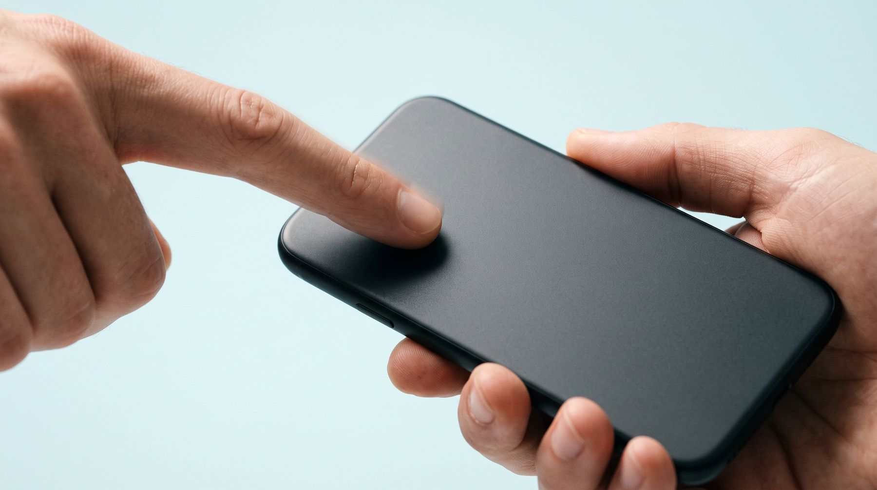 A finger tapping the back of a phone against a pale cyan backdrop